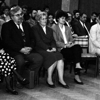 Formal indoor gathering with speaker addressing seated audience.