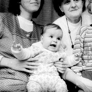Family portrait with three generations near Christmas tree.