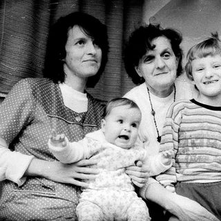 Family portrait with three generations near Christmas tree.