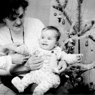 Family posing with baby near Christmas tree.