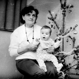 Woman holding baby near decorated Christmas tree.