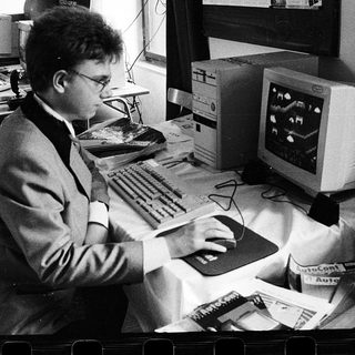 Man using early computer with CRT monitor and mouse.