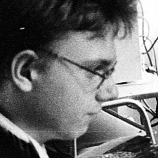 Man using early computer with CRT monitor and mouse.