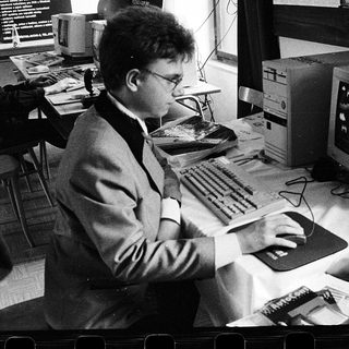 Man using early computer with CRT monitor and mouse.