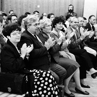 People applauding during an indoor event or meeting.