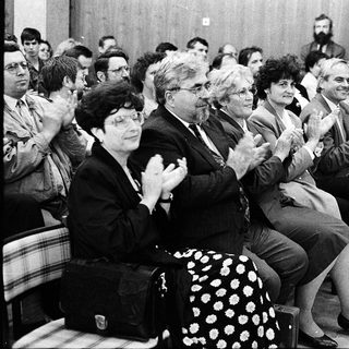 People applauding during an indoor event or meeting.