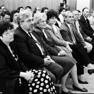 Group of people attending formal indoor meeting or conference.