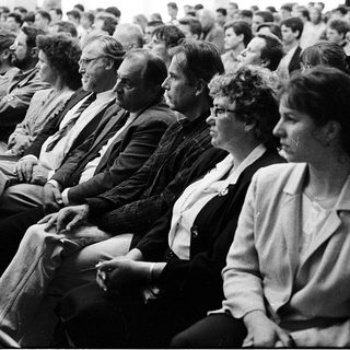 Group of people attentively seated in an indoor lecture or meeting.