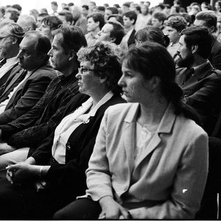 Group of people attentively seated in an indoor lecture or meeting.