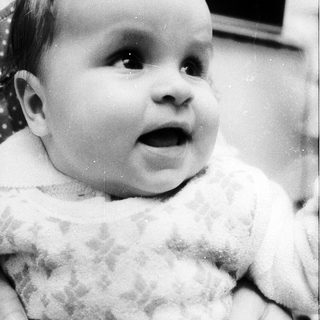Baby in cozy sweater, looking surprised.