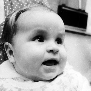 Baby in cozy sweater, looking surprised.