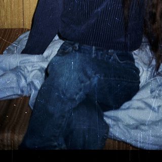 Person sitting on bed with long hair.