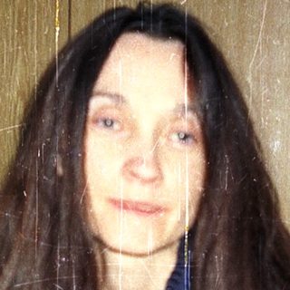 Woman sitting indoors with wet, long hair.