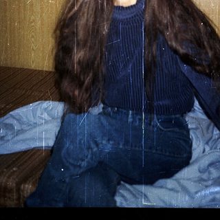 Woman sitting indoors with wet, long hair.