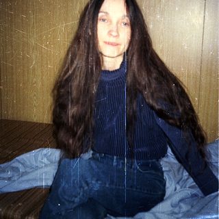 Woman sitting indoors with wet, long hair.