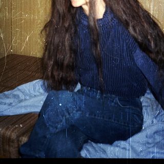 Person sitting on bed in casual attire.