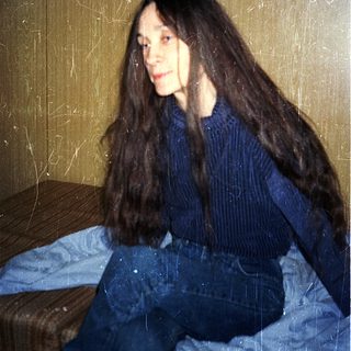 Person sitting on bed in casual attire.