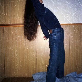 Person stretching long hair upward indoors.