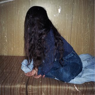 Person sitting on wet bench with head down.