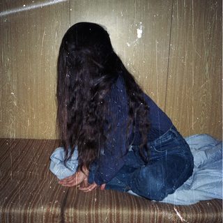 Person sitting on wet bench with head down.