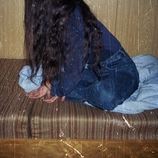 Person sitting on wet bench with head down.