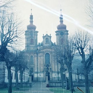 Baroque church with twin towers, viewed through rain.