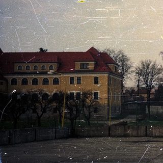 Empty urban courtyard with snow-covered rooftops and bare trees.