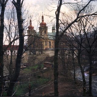 Baroque church with twin domes framed by bare trees.