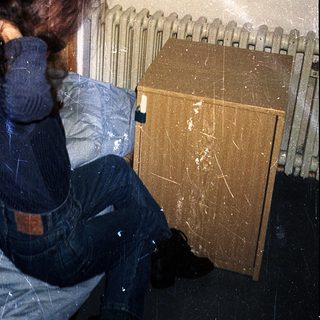 Person sitting on bed near radiator.