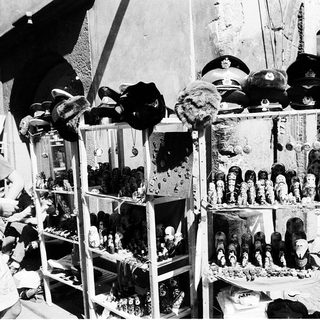 Vintage street vendor stall selling military hats and dolls.