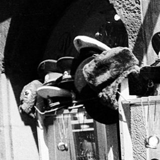Vintage street vendor stall selling military hats and dolls.