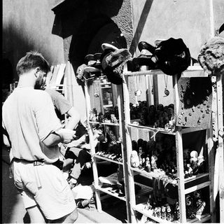 Vintage street vendor stall selling military hats and dolls.
