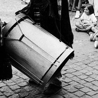 Street performance with musician and seated woman.