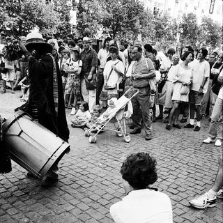 Street performance with musician and seated woman.