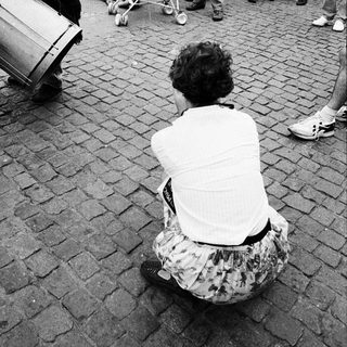 Street performance with musician and seated woman.