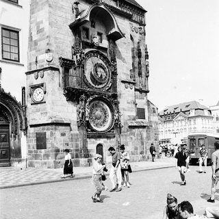 Historic astronomical clock tower with people observing.