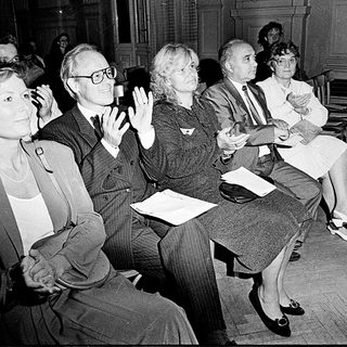 People attending a formal indoor event, clapping.