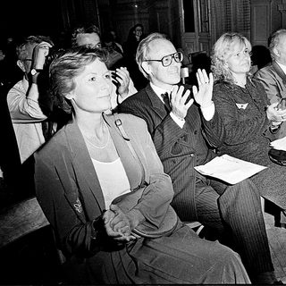 People attending a formal indoor event, clapping.