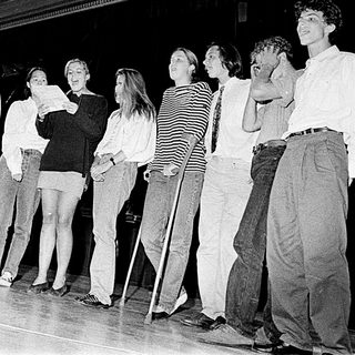 Group performing on stage in 1980s-style attire.