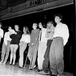 Group performing on stage in 1980s-style attire.