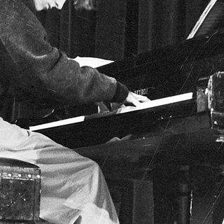 A pianist playing a grand piano on stage.
