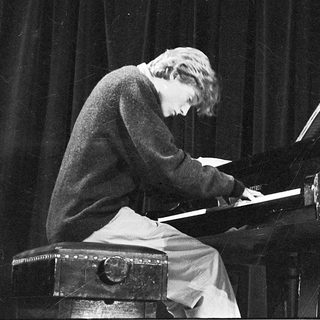 A pianist playing a grand piano on stage.