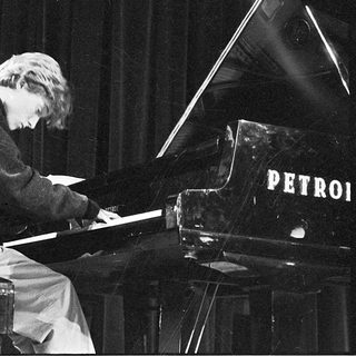 A pianist playing a grand piano on stage.
