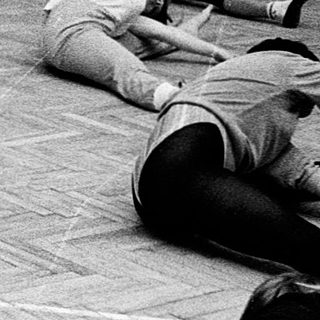 Group performing floor exercises in dance studio.