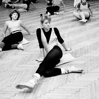 Group fitness or dance class in 1970s gym setting.