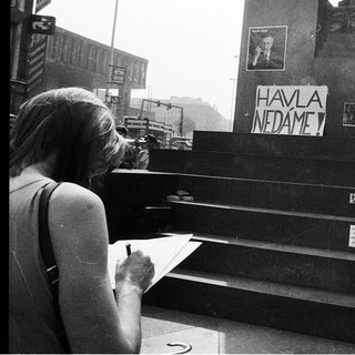Woman signing protest banner near monument.