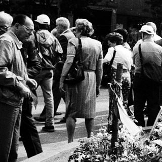 Memorial gathering with floral tributes and plaques.