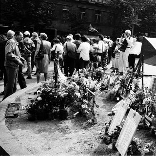 Memorial gathering with floral tributes and plaques.