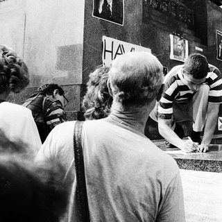 People signing a wall memorial.