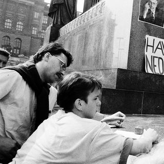 People paying respects at memorial with "Havel nedáme" sign.
